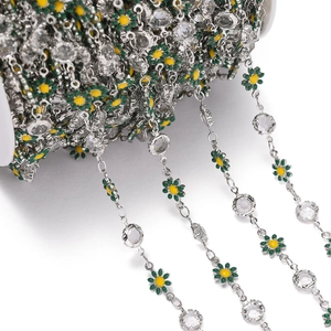 Macro shot of silver daisy chain with green enamel petals and clear crystal rhinestones