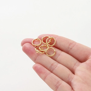 Mano sosteniendo anillos de cuentas chapados en oro 14K para hacer joyas DIY