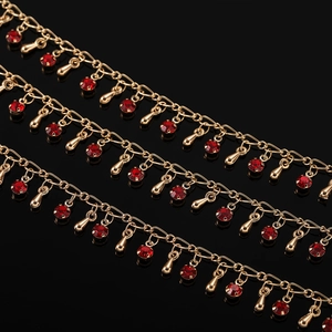 Détail d'une chaîne dorée avec cristaux rouges et pendentifs en forme de goutte