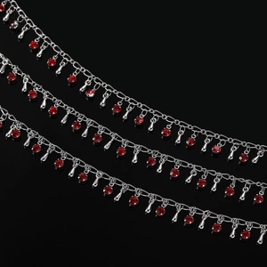 Détail d'une chaîne argentée avec sertis en cristal rouge et pendentifs en goutte