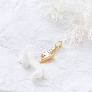 Macro detail of lightning bolt pendant with white mother of pearl inlay in 18K gold base