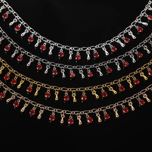 Détail de chaînes à franges en cuivre avec cristaux rouges et pendentifs en or et argent