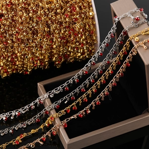Détail de chaîne cœur en cuivre avec cristaux rouges et grelots en or argent rose or