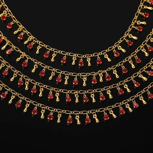 Gros plan détaillé d'un collier multicouche doré avec cristaux rouges et breloques gouttes