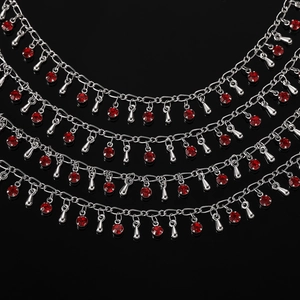 Détail d'une chaîne argentée à cinq couches avec cristaux rouges et pendentifs gouttes