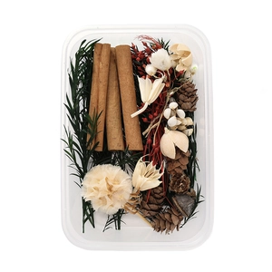 Macro shot of DIY kit with dried flowers, pine cones, and cinnamon sticks in a clear box