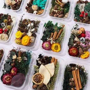 Flat lay of DIY dried flower kits with pine cones, cinnamon, and lemons in boxes