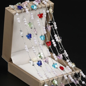 Detail of colorful butterfly crystal and pearl charms on a delicate silver chain
