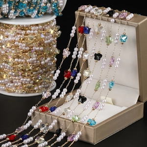 Detail of colorful butterfly beads and white pearls on a gold DIY jewelry craft chain