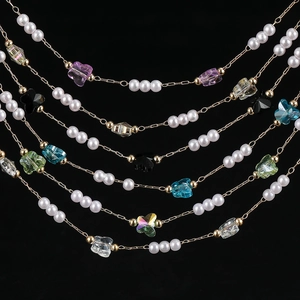 Detail of colorful butterfly crystals and white pearls on a gold DIY jewelry chain
