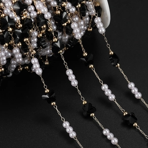 Close-up of DIY jewelry chain with black butterflies, white pearls and gold metal links