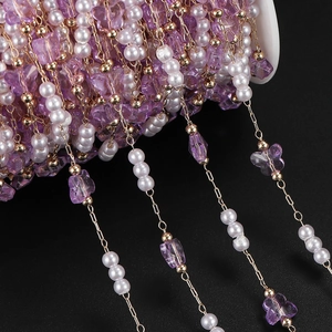 Macro view of purple butterfly beads and pearls on a gold chain for DIY jewelry craft