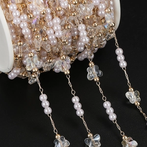 Macro detail of DIY golden jewelry chain with small pearls and iridescent butterflies
