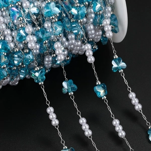Detailed view of sky blue butterfly crystal beads and white pearls on a silver chain