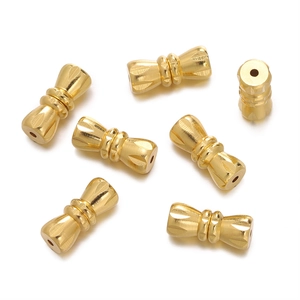 Close-up of golden dumbbell-shaped jewelry screw clasps with detailed radial engravings