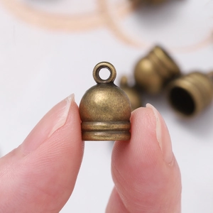 Close-up of vintage bronze tassel cap with top ring for DIY jewelry making and leather cord end