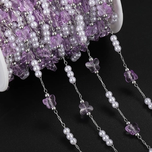 Detail of lavender butterfly charms and white pearls on a DIY jewelry chain reel