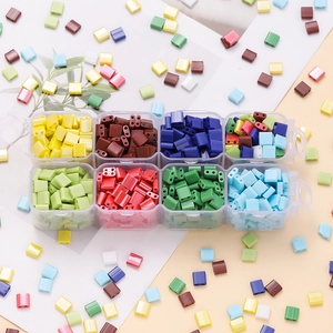 Macro view of two-hole glass cube beads in an 8-grid organizer for DIY jewelry making