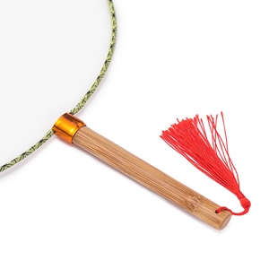 Close-up of bamboo handle with red tassel and green fabric border on traditional round fan