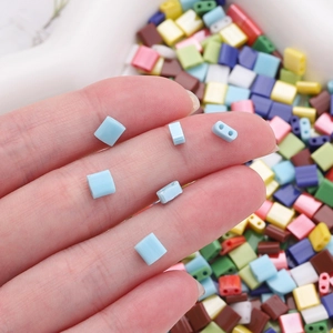 Macro detail of rectangle two-hole glass Tila beads in vibrant mixed colors for jewelry