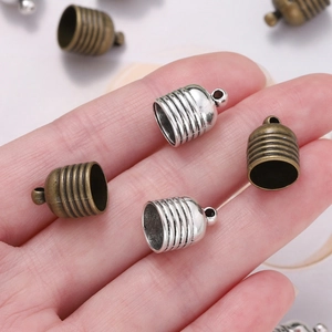 Macro detail of silver and bronze tassel end caps with stripe texture for DIY jewelry
