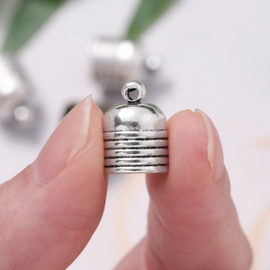 Macro view of vintage silver tassel end cap held by fingers for DIY jewelry making