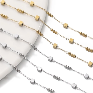 Detailed shot of gold and silver geometric chains with cube beads and round beads accents