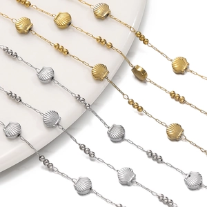 Macro detail of gold and silver stainless steel shell chains on a ceramic tray