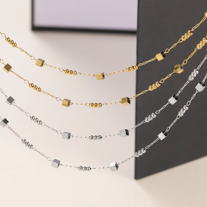 Detail of gold and silver fine chains featuring metal beads and polished cube elements