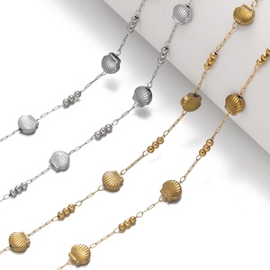 Detail of shell-shaped beads and round links on stainless steel gold and silver chains