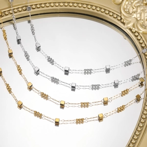 Macro view of gold and silver layered cube beaded chains on a vintage mirror surface