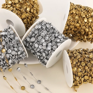 Macro view of shell-shaped metal chain and beads on spools for DIY jewelry making