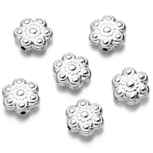 Detalle de cuentas plateadas de flores de seis pétalos con acabado brillante para joyería DIY