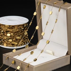 Detail of gold vacuum plated stainless steel square bead chain on spool and in a jewelry gift box