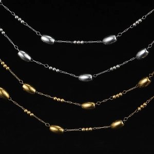 Detailed macro of gold and silver stainless steel chain with oval beads on black background