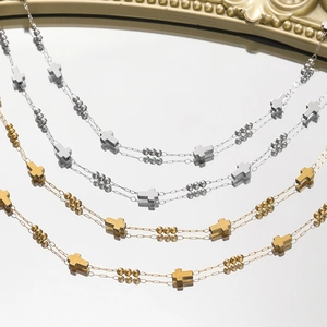 Collana doppia catena con croci e perle lucide in oro e argento su sfondo a specchio