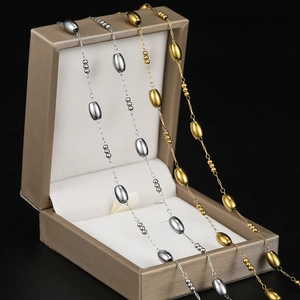 Macro detail of gold and silver oval bead chains on a jewelry display box