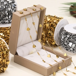 Close-up of golden heart and bead chain charms on spools for DIY jewelry making