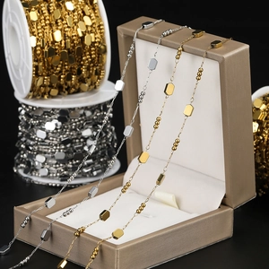 Macro detail of geometric DIY chain with square links and hexagonal beads in gold and silver