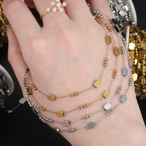 Detail of square links chain and hexagon charm necklace in gold and silver finish