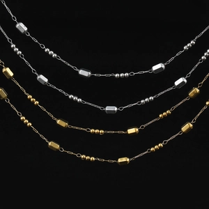 Detail of gold and silver beaded cross chains with hexagonal prisms on black background