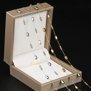 Close-up of gold and silver beaded box chains on a luxury jewelry box display