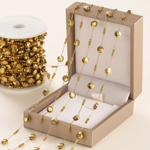 Detail of gold oval link chain with polished round discs and beads for DIY jewelry making