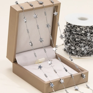 Detail of silver stainless steel chain featuring polished star pendants and small round beads