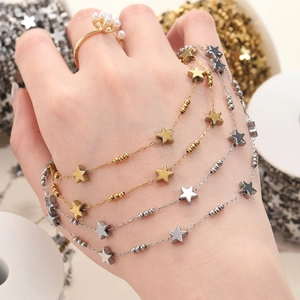 Star charm bracelets in gold and silver finish layered on wrist for detailed texture