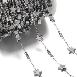 Close-up of stainless steel chain roll with beads and star pendants for DIY jewelry