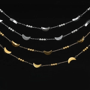 Close-up of stainless steel chain bracelets with crescent moon charms and tiny round beads