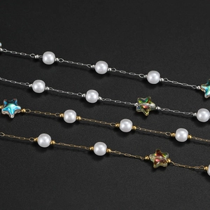 Detailed macro view of 18K gold and silver star chains with white acrylic pearls
