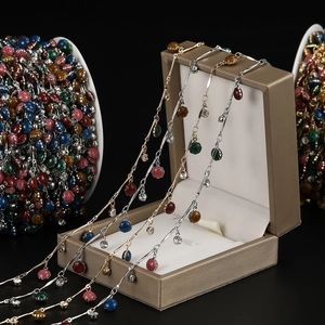 Dettaglio di catene placcate oro con ciondoli a fiore glitterati colorati e cristalli