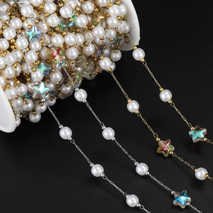Macro detail of DIY jewelry chain with pearls, gold links and iridescent star charms
